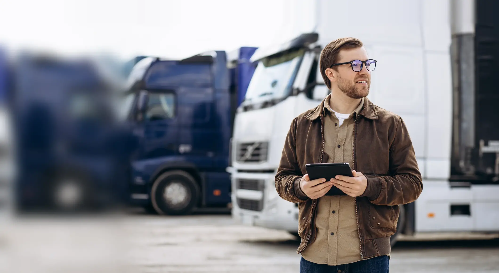 Fleet manager with a tablet in front of parked trucks